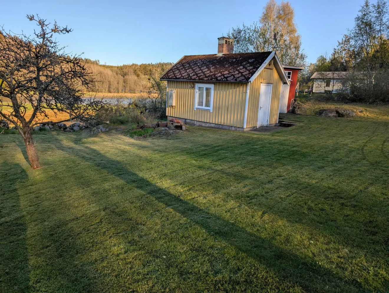 Trädgårdshjälp i Lysekil: nyklippt gräsmatta vid en gul stuga